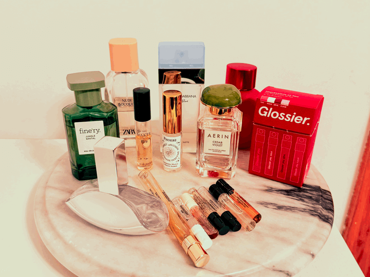 A marble platter sits on the top of a dresser with 9 perfume bottles, 6 sample vials, and a box with 4 more samples.